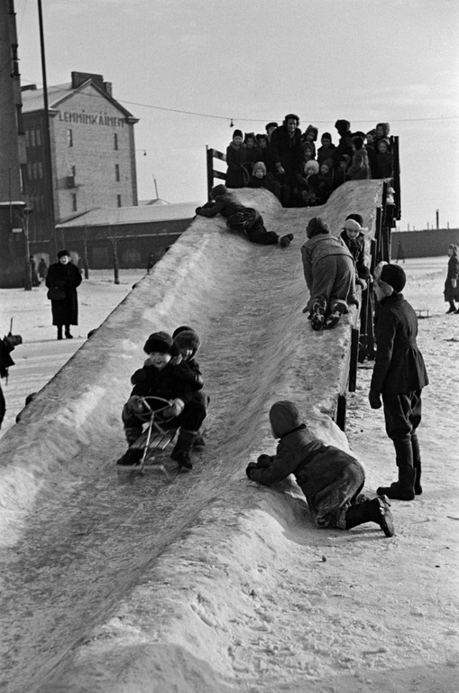 1950 . Jäämäki ja lapsia laskemassa mäkeä Hakaniementorin kaakkoiskulmassa. Taustalla Hakaniemenkatu 2.