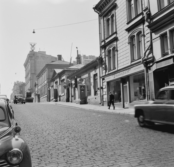 1954 . Korkeavuorenkatu 38, 36, 34, 32. Etummaisina ovat erikoisliike Budapest ja kahvila Bebe. Katolla on Veikkauksen mainos.